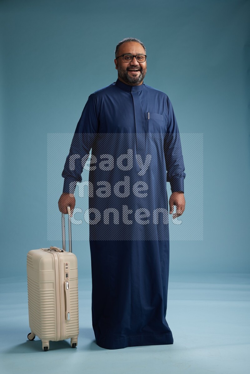 Saudi Man without shimag Standing pulling travel bag on blue background