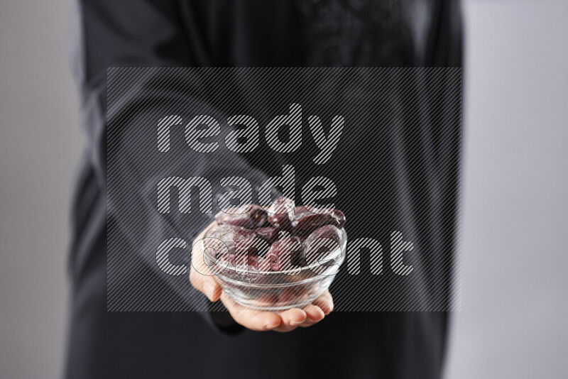 امرأة ترتدي عباءة تحمل أنواع مختلفة من التمر في أوضاع متعددة