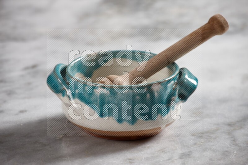 Multicolored pottery bowl with wooden honey dipper in it on grey marble background