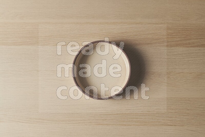 A beige pottery oven bowl on light wooden background