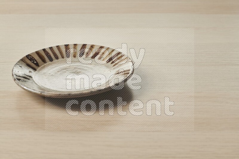 A multicolored pottery plate on light wooden background
