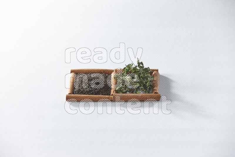 مربعان من أعواد القرفة ممتلئان بالشاي الأسود والنعناع المجفف علي خلفية بيضاء