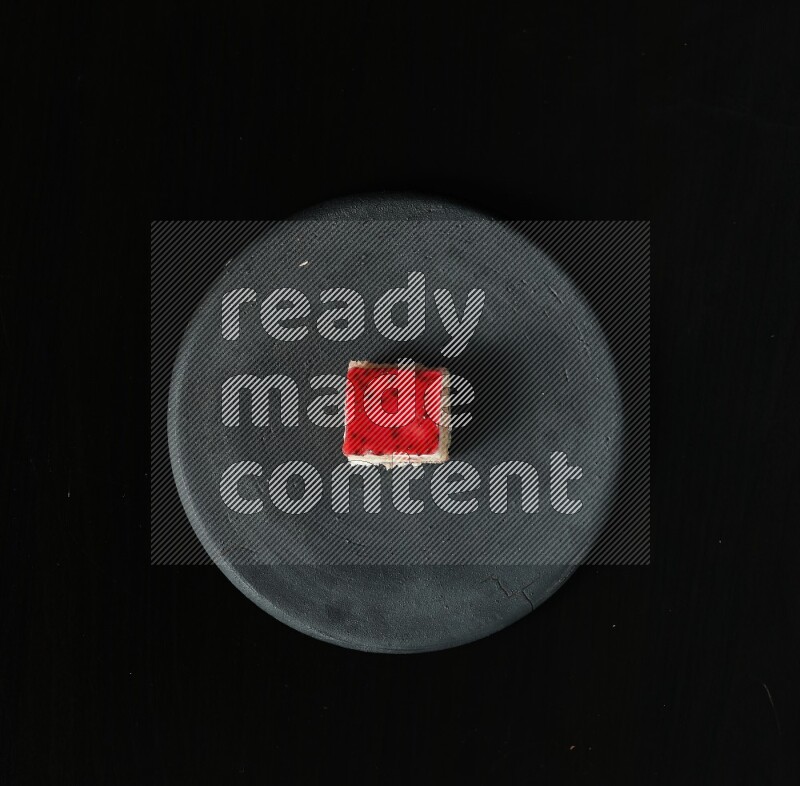 Assorted desserts in a black pottery plate on black background