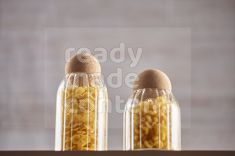 Raw pasta in glass jars on beige background