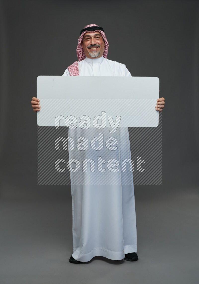 Saudi man with shomag Standing holding social media sing on gray background
