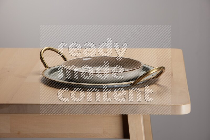 multicolored plate placed on a rounded stainless steel tray with golden handels on the edge of wooden table
