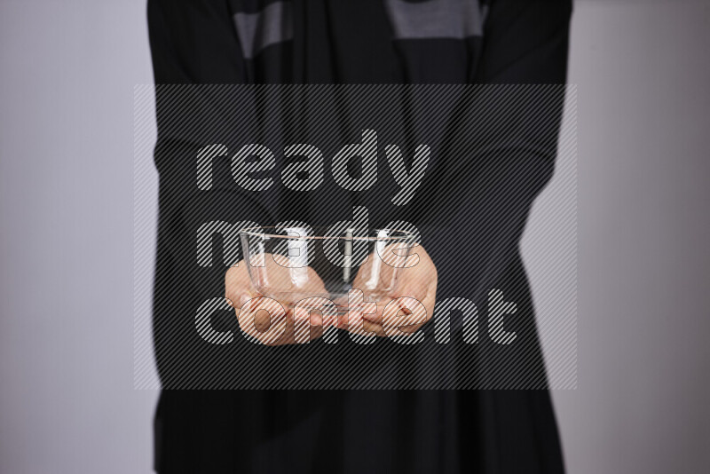 A woman in black abaya holding different glassware in different positions