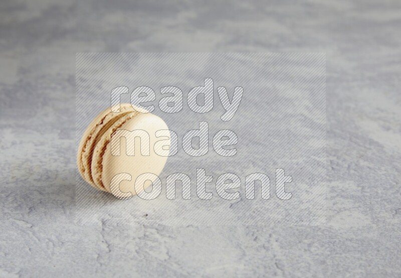 45º Shot of white marbleCaramel fleur de sel macaron on white  marble background