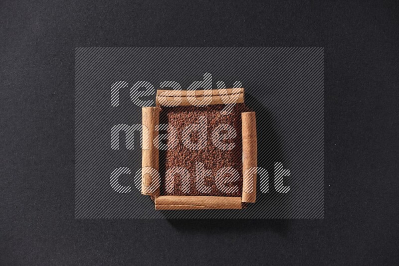 A single square of cinnamon sticks full of garden cress on black flooring