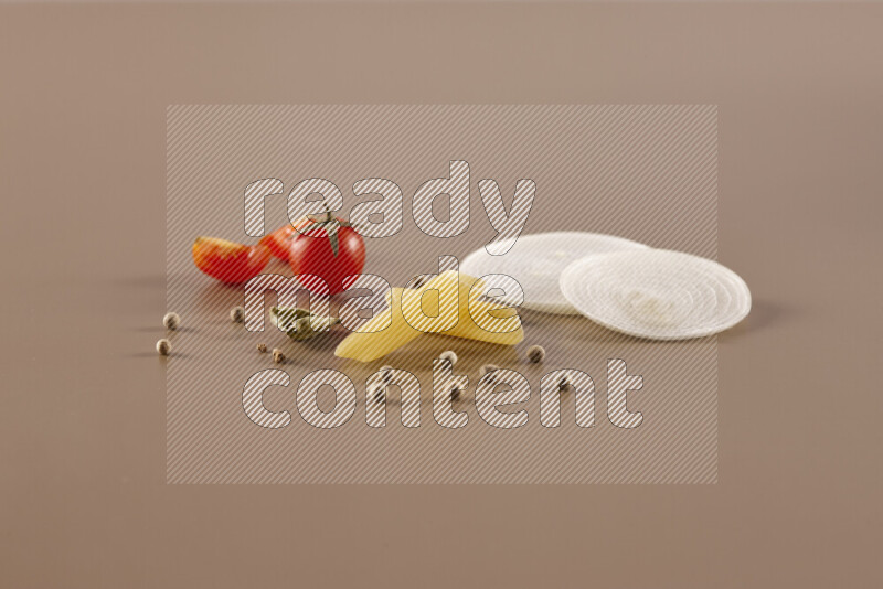 Raw pasta with different ingredients such as cherry tomatoes, garlic, onions, red chilis, black pepper, white pepper, bay laurel leaves, rosemary and cardamom on beige background