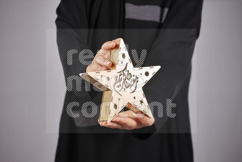 A woman in black abaya holding different ramadan lanterns in different positions