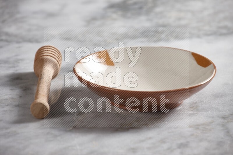 Multicolored pottery plate with wooden honey dipper on the side on grey marble background