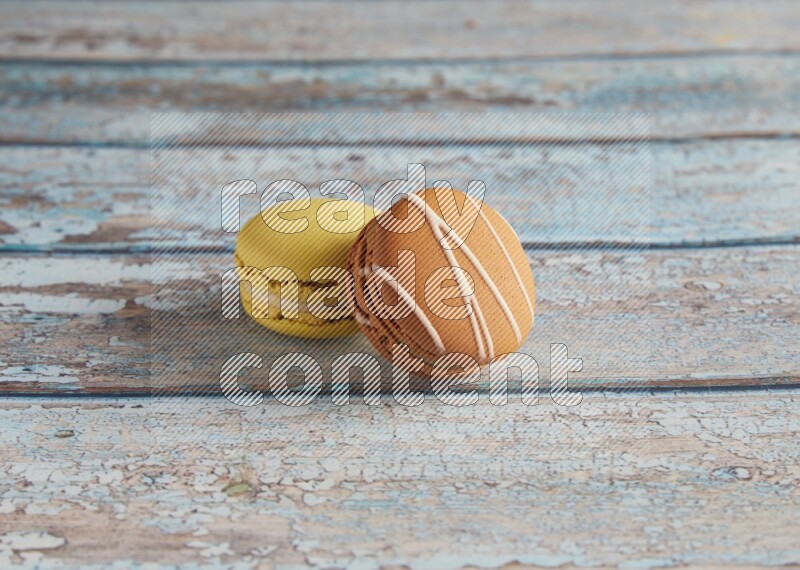 45º Shot of of two assorted Brown Irish Cream, and Yellow Lime macarons on light blue background