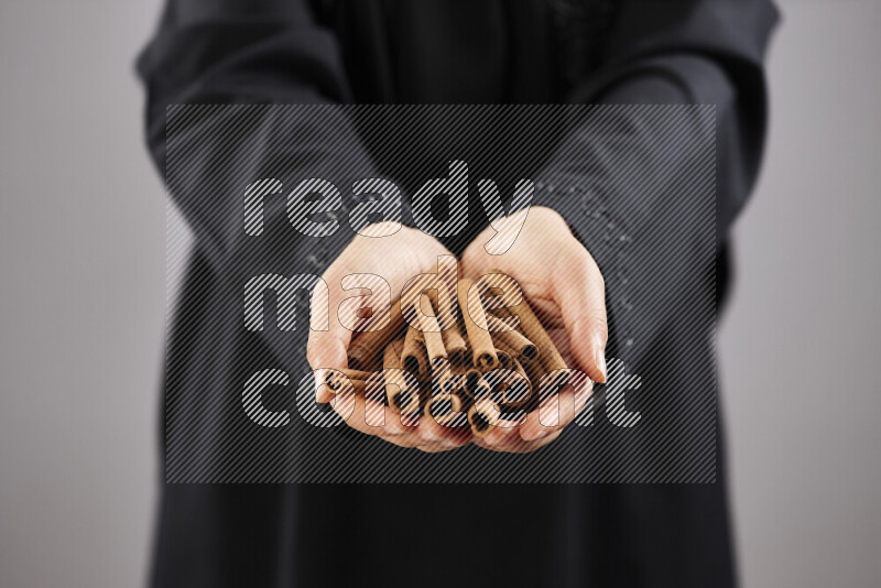 Woman in abaya holding different kinds of spices in different positions