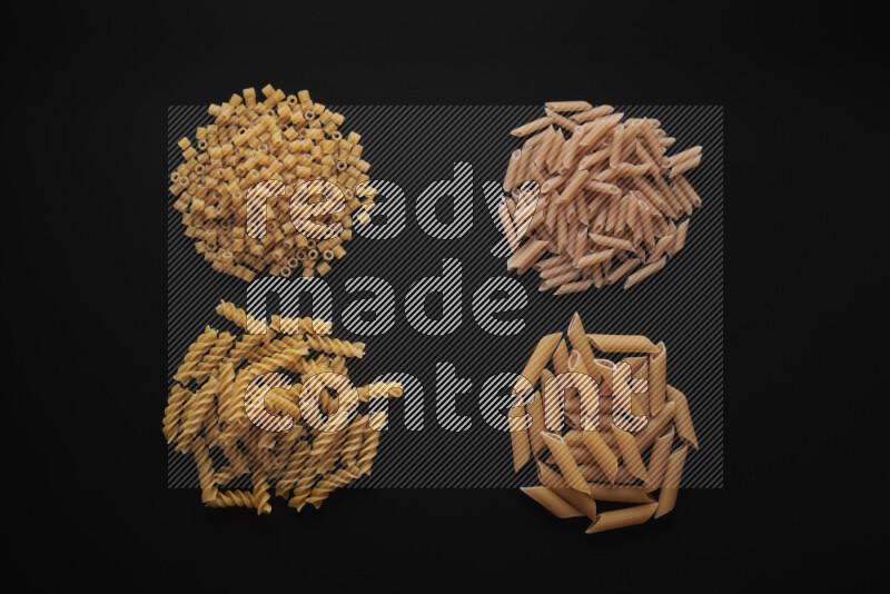 Different pasta types in bunches on black background