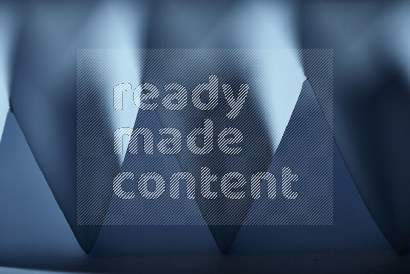 صورة مجردة مقربة تظهر طيات ورقية هندسية حادة بتدرجات اللون الأزرق