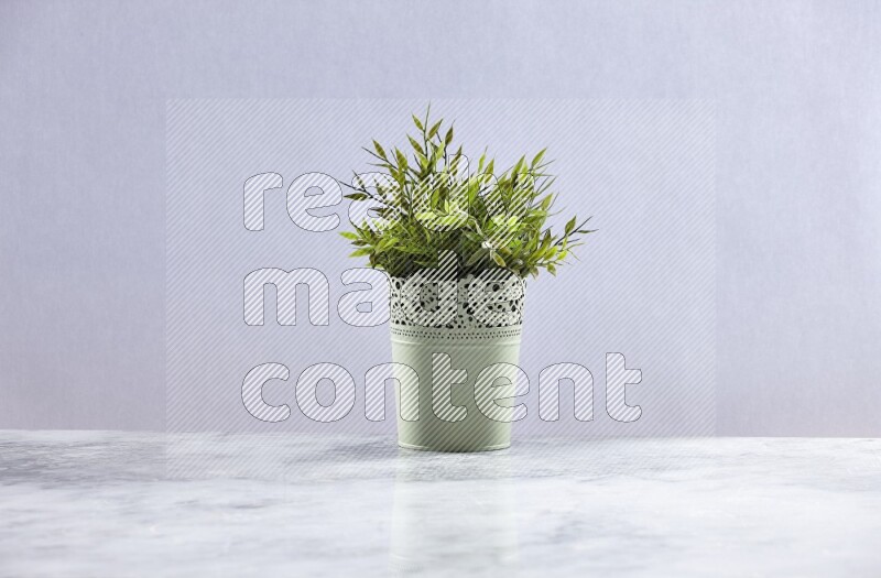 Artificial plant in green decorative pot on grey marble background