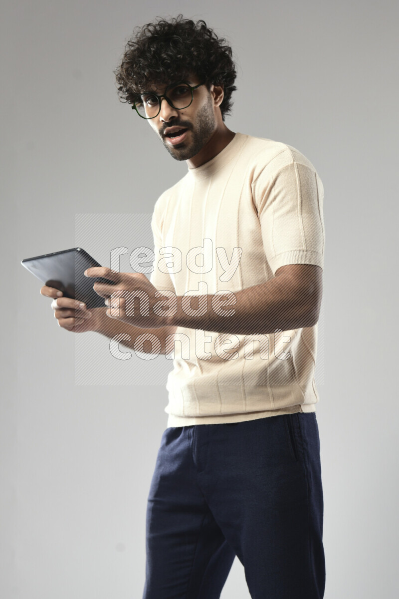 A man wearing casual standing and gaming on a tablet on white background