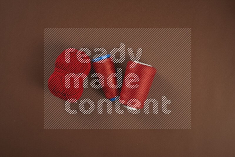 A red collection of sewing and tailoring tools arranged on a brown background