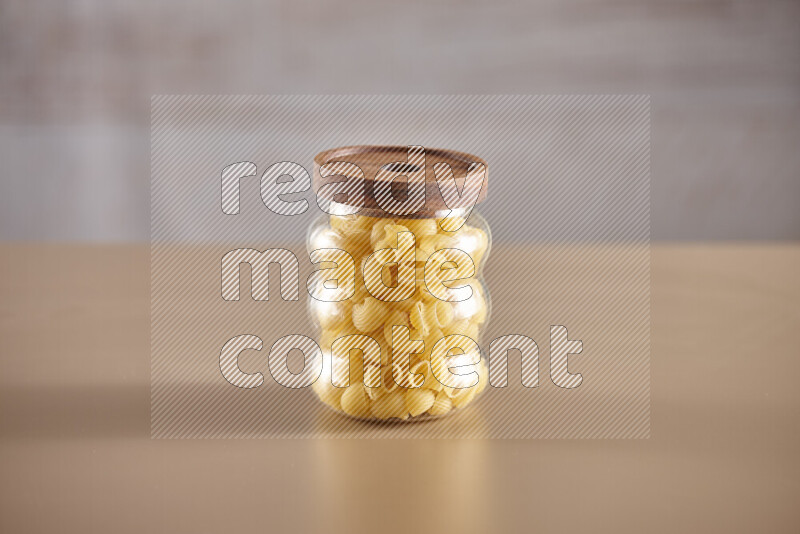 Raw pasta in glass jars on beige background
