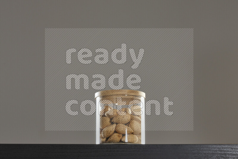 Almonds in a glass jar on black background