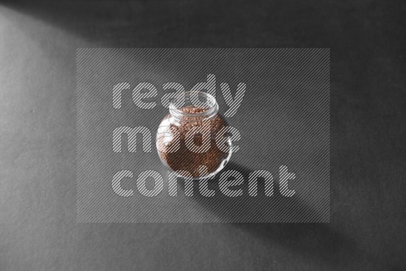 حبوب الكتان في وعاء زجاجي علي خلفية سوداء