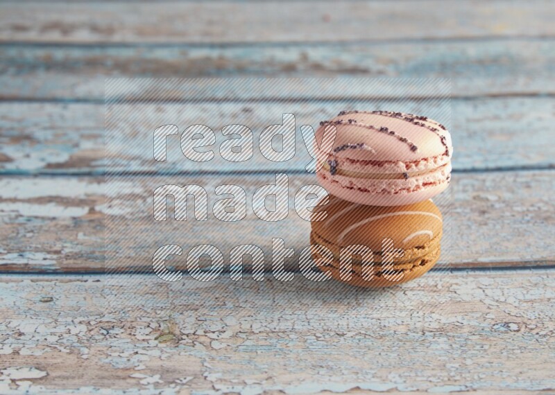 45º Shot of of two assorted Brown Irish Cream, and pink orange blossom  macarons on light blue background