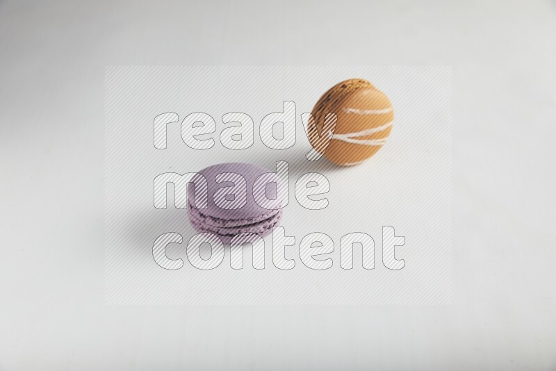 45º Shot of of two assorted Brown Irish Cream, and Purple Blueberry macarons on white background