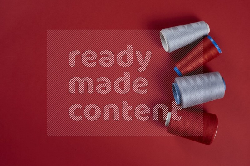 A grey collection of sewing and tailoring tools arranged on a red background