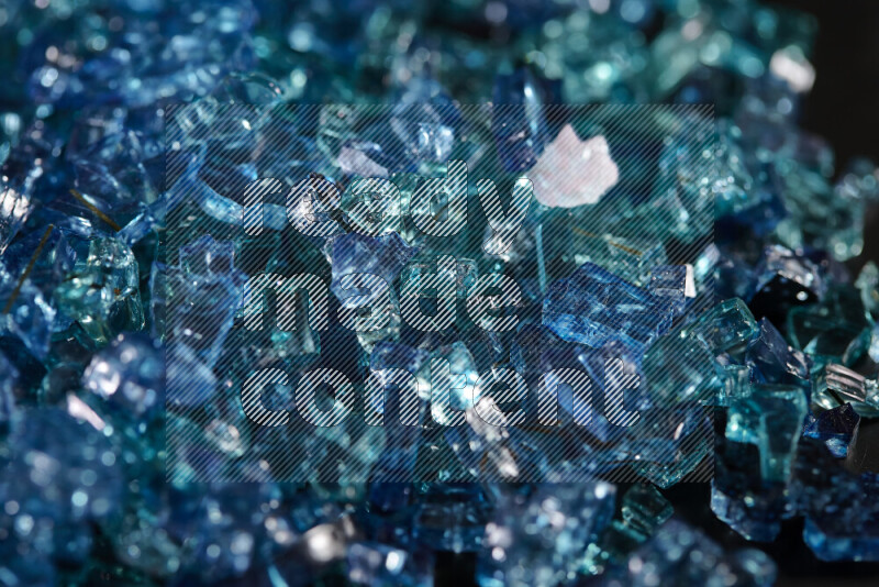 Transparent blue fragments of glass scattered on a black background