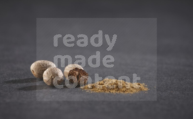 Nutmeg seeds with nutmeg powder beside it on a black flooring in different angles