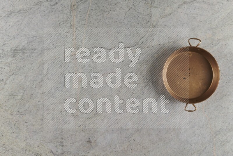 A small copper pan on grey marble background