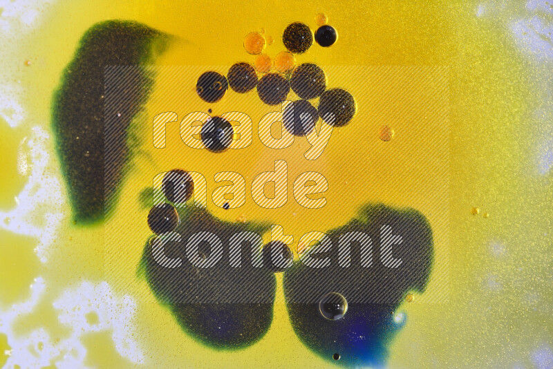 Close-ups of abstract yellow, blue and green watercolor drops on oil Surface on white background