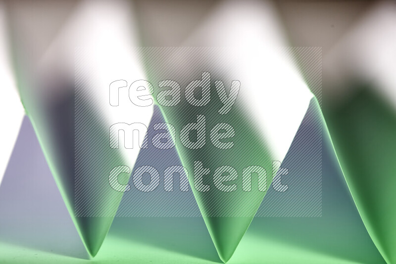 A close-up abstract image showing sharp geometric paper folds in white and green gradients