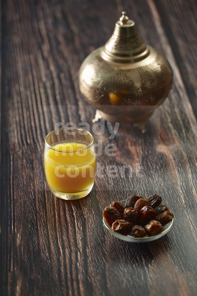 A golden lantern with different drinks, dates, nuts, prayer beads and quran on brown wooden background