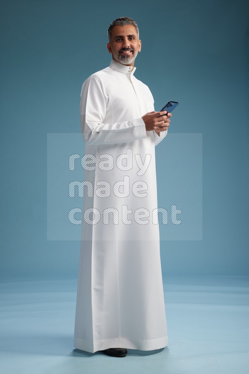 Saudi man waring thob texting on blue background