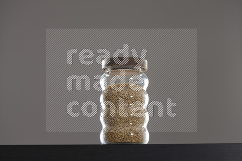 Hulled wheat in a glass jar on black background