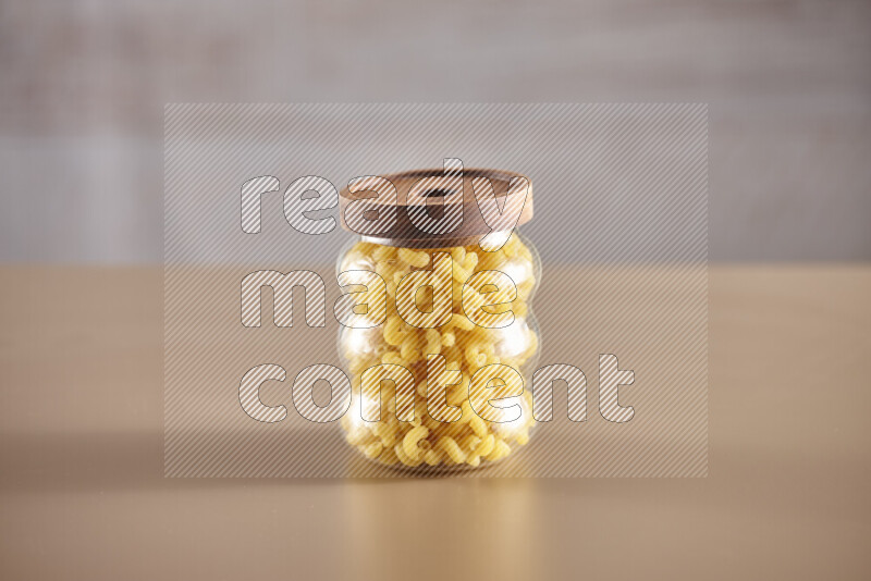 Raw pasta in glass jars on beige background