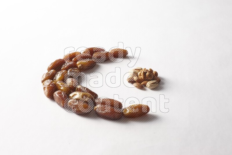 Dates in a crescent shape with nuts on white background