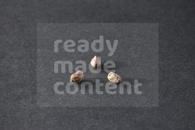 3 peeled pistachios on a black background in different angles