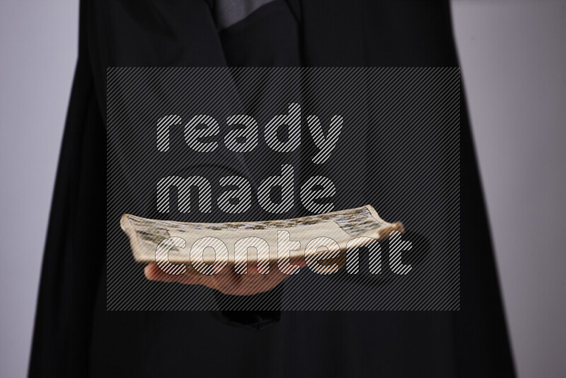 A woman in black abaya holding different pottery essentials in different positions