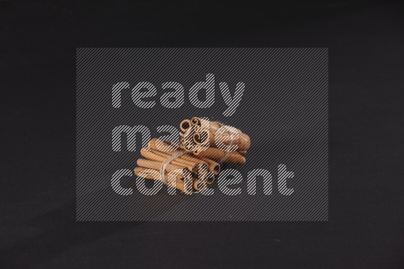 Two bounded stacks of cinnamon sticks on black background