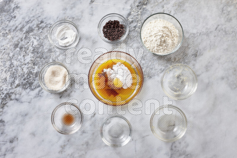Cookies step by step with its ingredient, flour, butter, brown sugar, egg, vanilla extract, white sugar, chocolate chips and baking soda on grey marble background