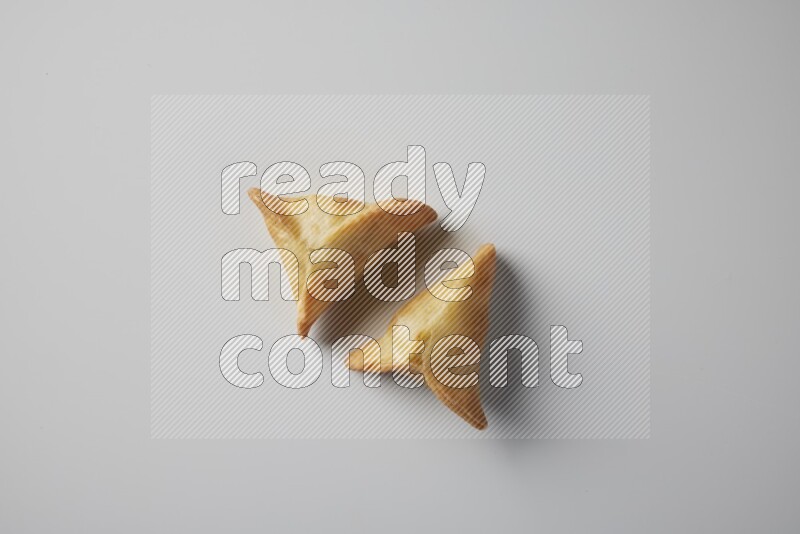 Two fried sambosa from a top angle on a white background