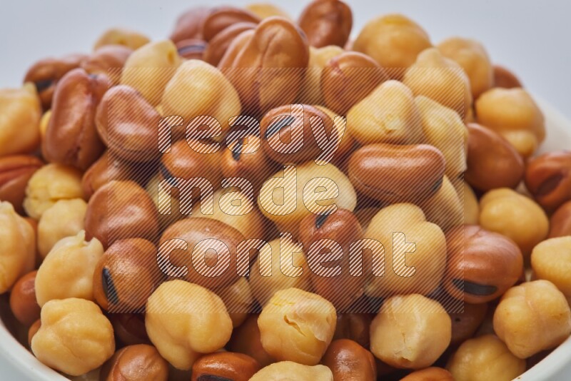 Close up shot of cooked fava beans (foul) & chickpeas on white background