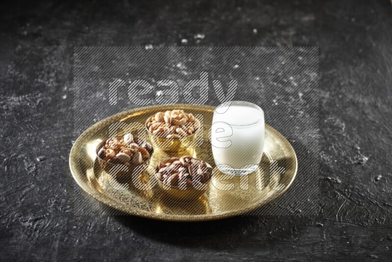 Nuts in metal bowls with sobya on a tray in dark setup