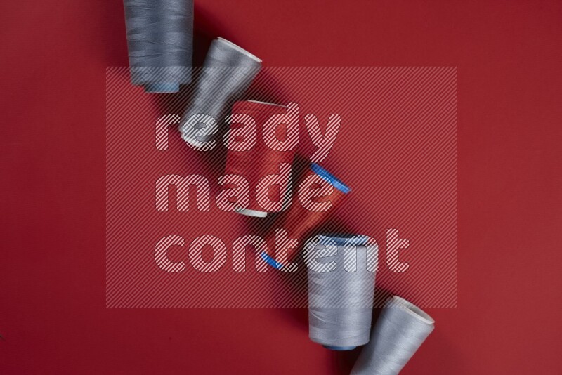 A grey collection of sewing and tailoring tools arranged on a red background