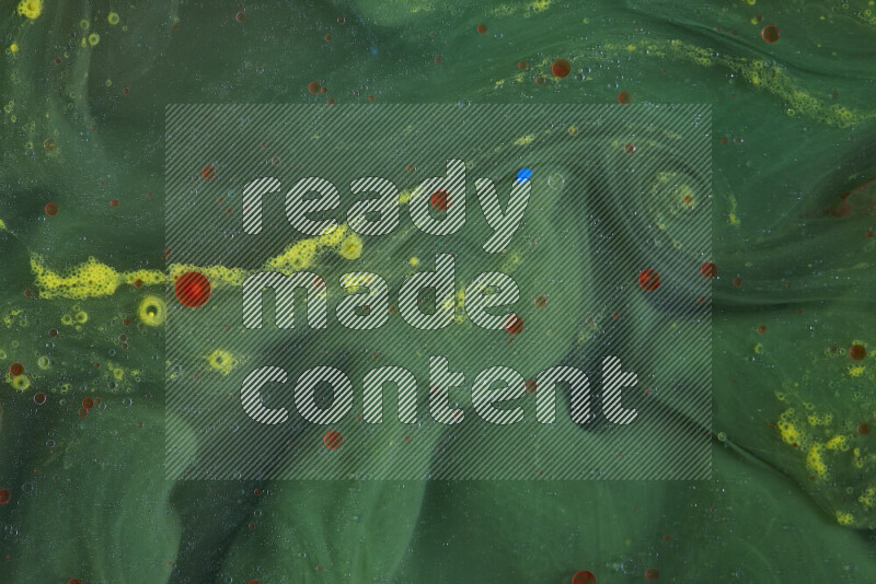 The image captures a dramatic splatter of red, green and yellow paints over the backdrop