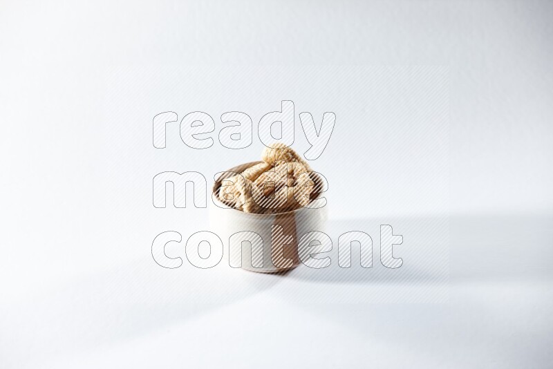 A beige ceramic bowl full of dried figs on a white background in different angles
