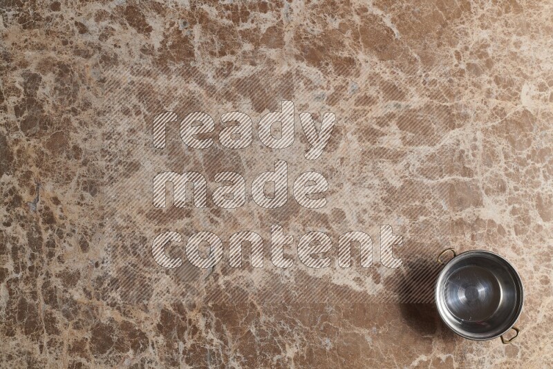 A small copper pot on beige marble background